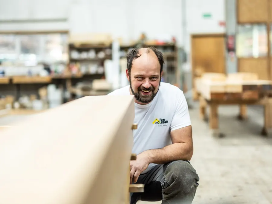 Anton Waldner lachend hinter Holzbalken
